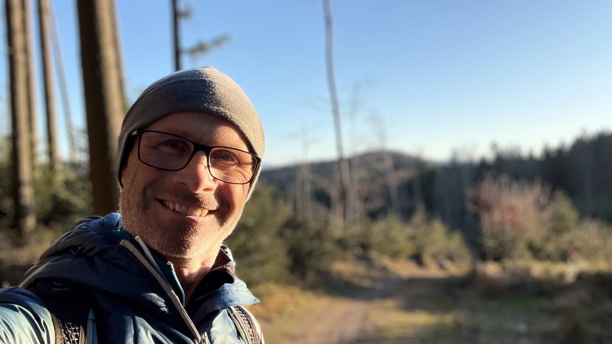 Christian Hosner lächelnd auf einem Waldweg in den Bergen